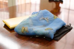 Blue silk butterfly scarf with butterfly illustrations on a polished wood table