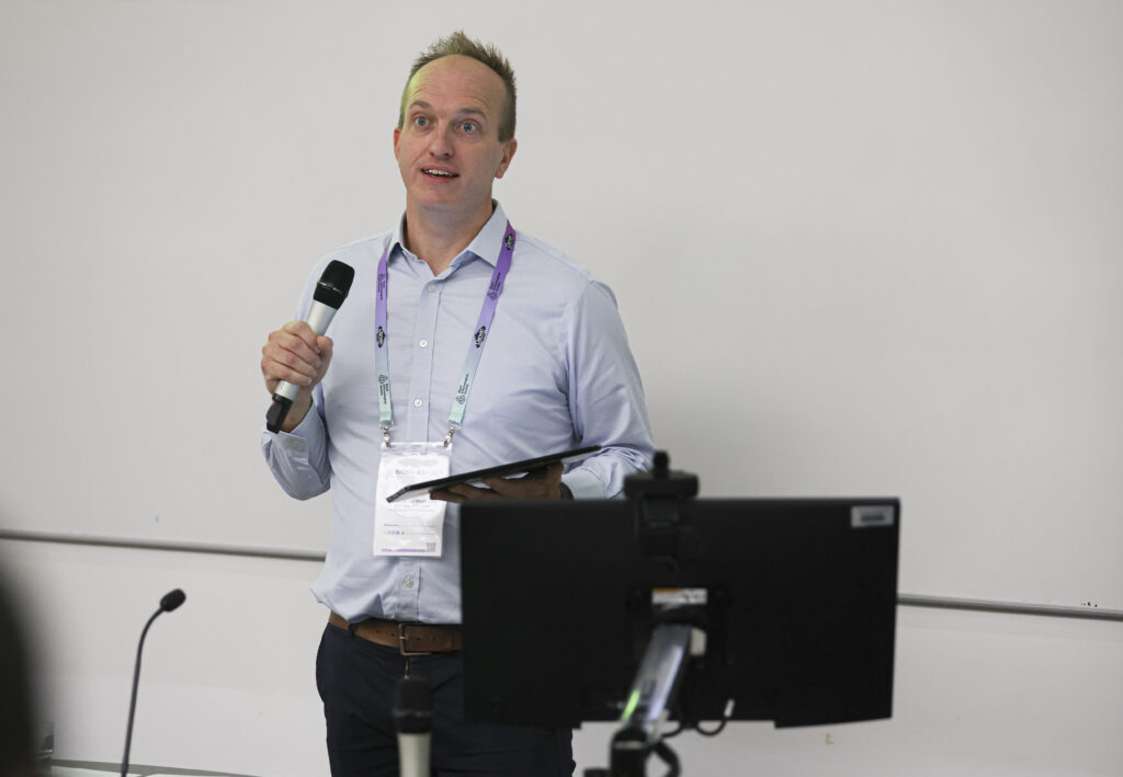 Simon Ward, RES CEO with a microphone introducing the audience to a conference